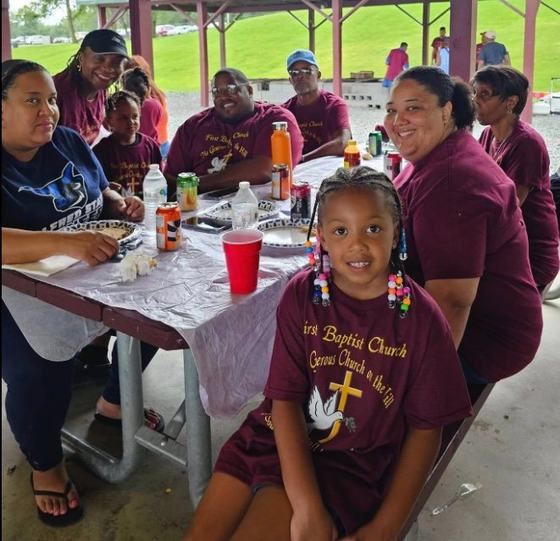 The Williams family smiling at a picnic table during the church outing